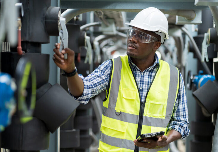 Male plumber engineer working at sewer pipes area at construction site. African American male engineer worker check or maintenance sewer pipe network system at construction sit