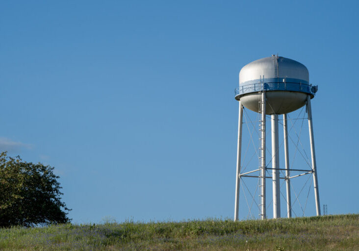 Watertower in a field against a blue sky.