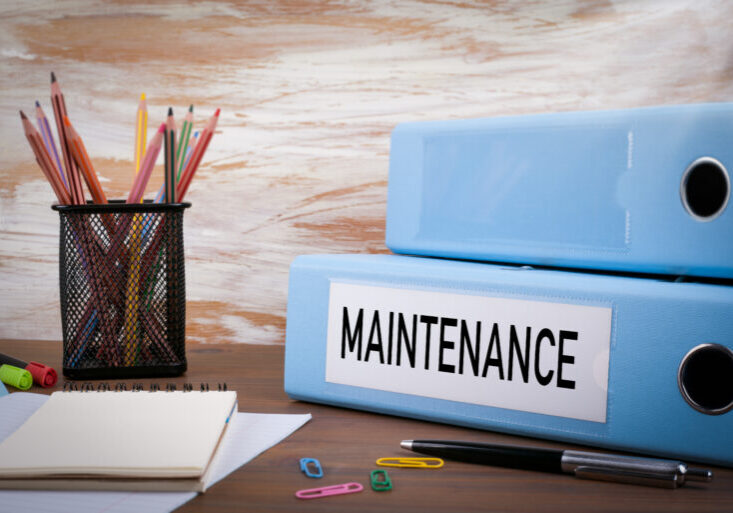 Maintenance, Office Binder on Wooden Desk. On the table colored pencils, pen, notebook paper